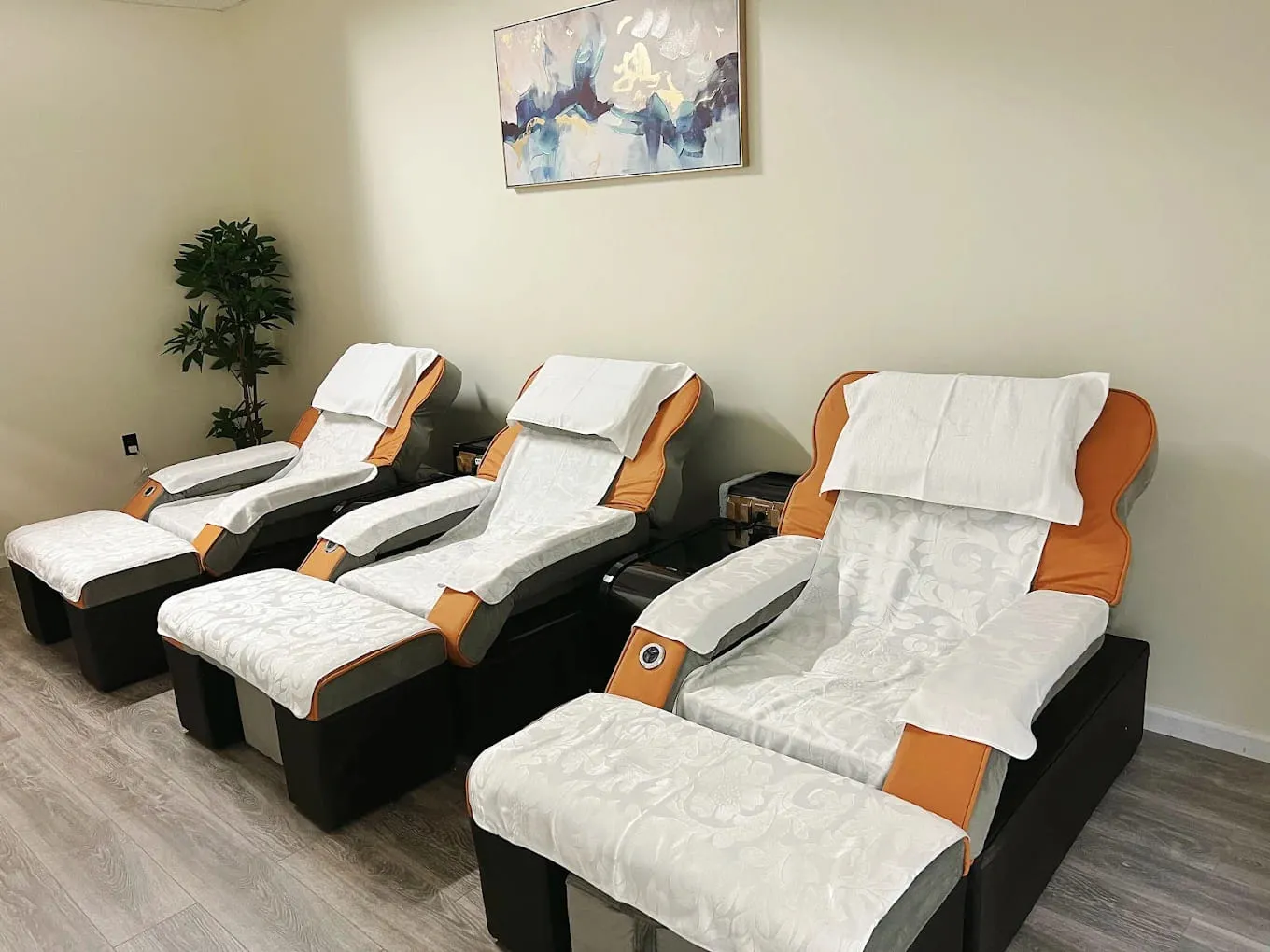 Row of three reflexology recliners with covered footrests under a framed abstract painting at Crystal Massage in Wichita, KS